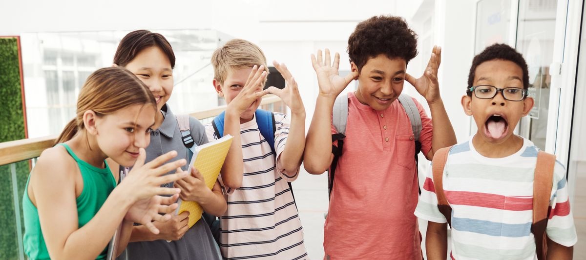 A group of school students laughing and making playful poses in a hallway